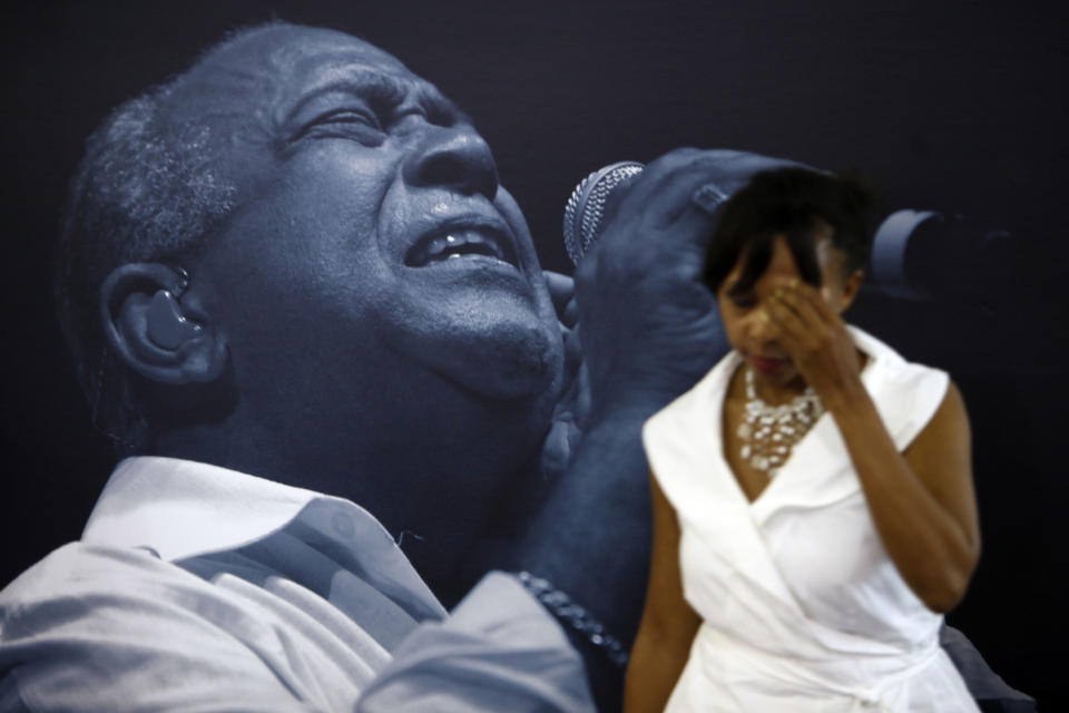 A woman walks by a giant photo poster of Cheo Feliciano during his funeral at the San Juan Coliseum in Puerto Rico, Saturday April 19, 2014. Feliciano, a member of the Fania All Stars died in a car crash early Thursday morning when he hit a light post before dawn in the northern suburb of Cupey in San Juan. (AP Photo/Ricardo Arduengo)