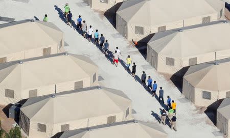 Immigrant children now housed in a tent encampment under the new "zero tolerance" policy by the Trump administration are shown walking in single file at the facility near the Mexican border in Tornillo, Texas, U.S. June 19, 2018. REUTERS/Mike Blake/Files