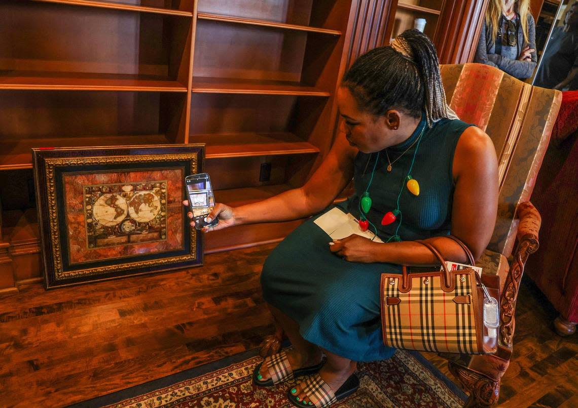 Attorney Kaysia M. Earley takes a picture of a framed world map she bid on during an auction hosted by Auctions4America to buy pieces of La Maison Blanche —the White House — a 1930s neoclassical estate on the Intracoastal in Fort Lauderdale on Saturday, Dec. 23, 2023. The home will be demolished in a couple weeks, and will be replaced by a 20,000-square-foot modernist home.