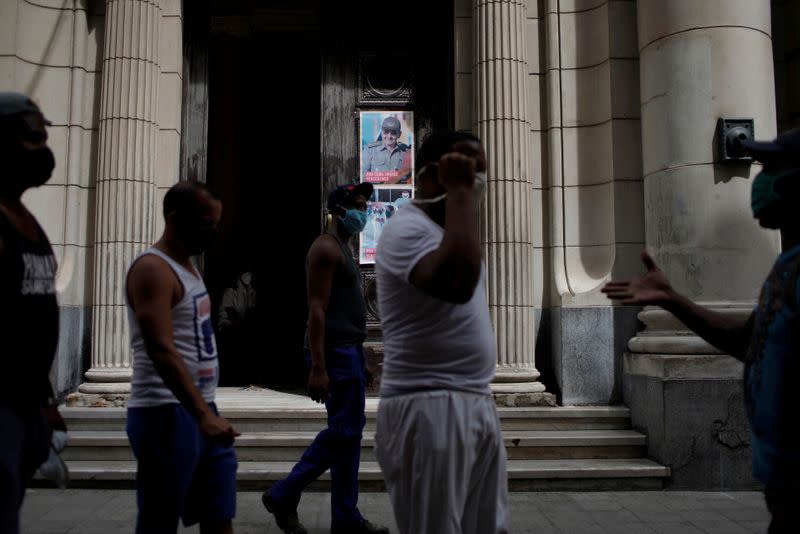 People walk on the street near an image of former Cuban President Raul Castro in Havana, Cuba