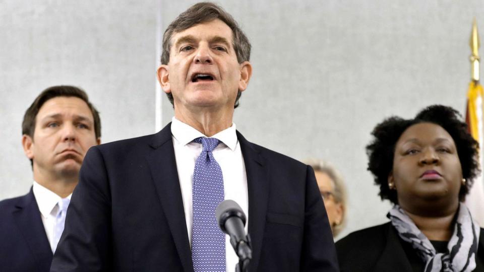 PHOTO: Dr. Scott Rivkees speaks to the media as he is flanked by, Gov. Ron DeSantis, left, and Deputy Secretary for Health Dr. Shamarial Roberson, right, March 2, 2020, in Tampa. (Chris O'meara/AP, FILE)