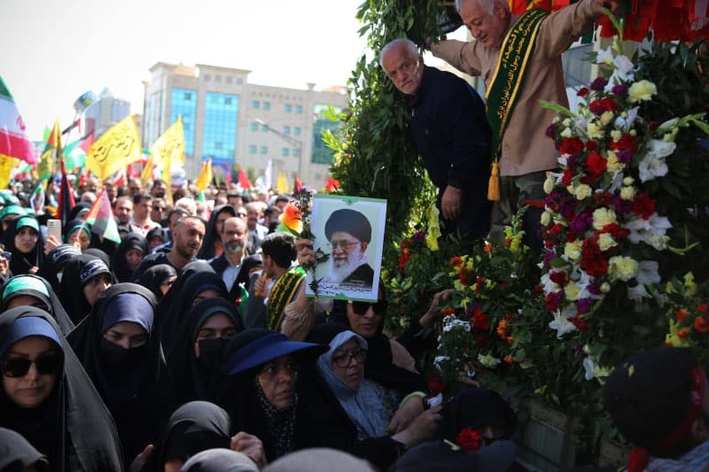 An Iranian mourner woman shows a poster portrait of Iranian Supreme Leader Ayatollah Ali Khamenei (C) next to a truck carrying the coffins of members of the Islamic Revolutionary Guard Corps (IRGC)  who were killed in an airstrike on the Iranian consulate building in Syria's capital Damascus, during their funeral in Tehran. Rouzbeh Fouladi/ZUMA Press Wire/dpa