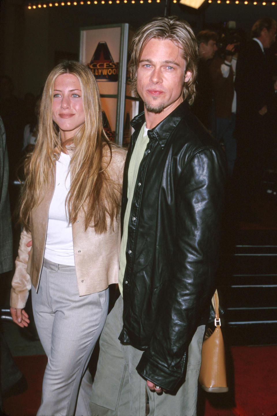 Jennifer Aniston and Brad Pitt walk the red carpet, with Jennifer in a casual chic outfit and Brad donning a leather jacket and relaxed attire