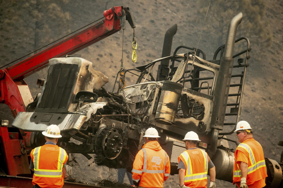 A crane lifts a truck scorched by the Delta Fire on Interstate 5 in the Shasta-Trinity National Forest, Calif., on Thursday, Sept. 6, 2018. The highway remains closed to traffic in both directions as crews battle the blaze. (AP Photo/Noah Berger)