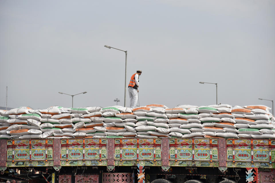 An Afghani truck driver ties a rope as trucks carrying wheat from India wait to pass through the Attari-Wagah border between India and Pakistan, near Amritsar, India, Tuesday, Feb.22, 2022. Last week, Pakistan officials said the country would allow nuclear rival India to deliver wheat to Afghanistan, where millions are struggling through acute food shortages. The arrangement comes more than three months after India announced it would deliver 50,000 metric tons of wheat and life-saving medicine to Afghanistan. (AP Photo/Prabhjot Gill)