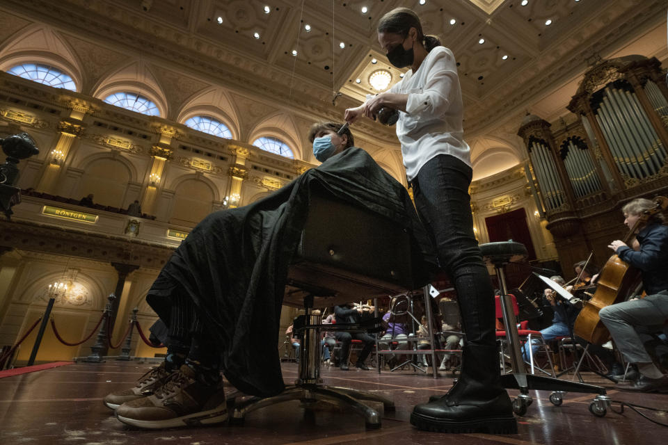 People get a haircut during a rehearsal at the Concertgebouw in Amsterdam, Wednesday, Jan. 19, 2022, as Dutch museums, theaters and concert halls played host Wednesday to businesses that are allowed to open to customers as a protest against their own continuing lockdown closures. (AP Photo/Peter Dejong)