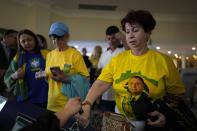 Maria Marquez, 63, a Brazilian who lives in the U.S., wears a shirt with an image of Brazil's right wing former President Jair Bolsonaro as she gets her hand stamped after arriving to hear him speak, at an event hosted by conservative group Turning Point USA at Trump National Doral Miami, Friday, Feb. 3, 2023, in Doral, Fla. (AP Photo/Rebecca Blackwell)