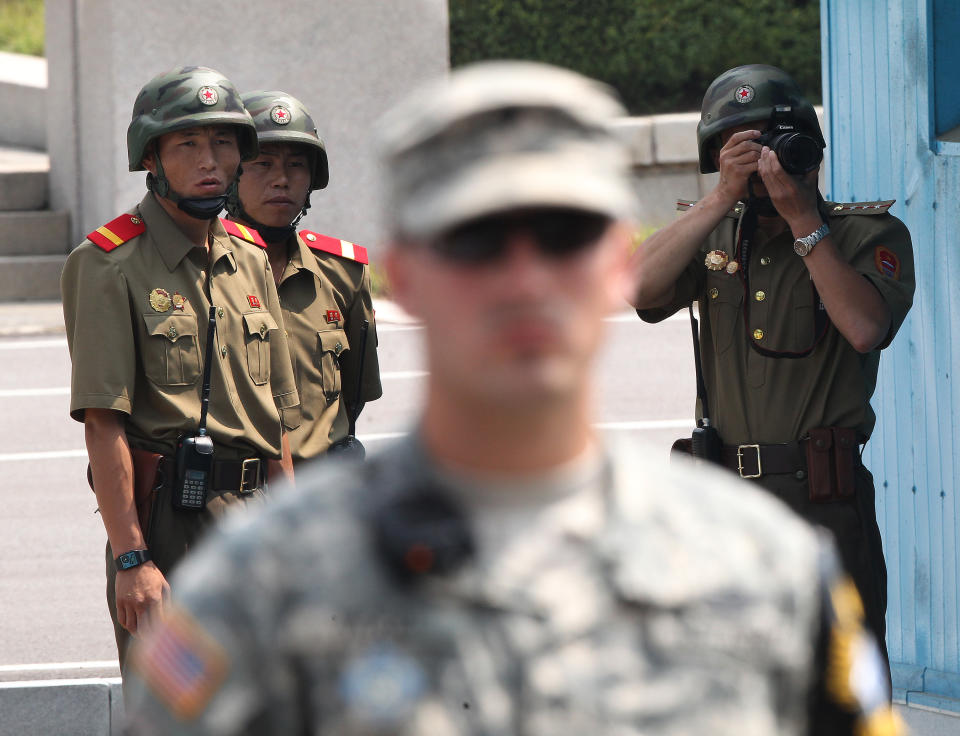 North Korean soldiers watch the south side as a U.S. Army soldier stands guard after a ceremony marking the 61th anniversary of the signing of the armistice agreement that ended the Korean War, at the border villages of Panmunjom, South Korea, Sunday, July 27, 2014. North Korea fired a short-range ballistic missile into waters off its east coast on Saturday, a South Korean defense official said, adding to its unusually high number of weapons tests this year. (AP Photo/Ahn Young-joon)