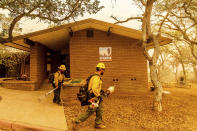 As the KNP Complex Fire approaches, U.S. Forest Service firefighters Armando Flores, right, and Heron Hilbach-Barger clear vegetation around structures at the Ash Mountain headquarters in Sequoia National Park, Calif., on Wednesday, Sept. 15, 2021. The blaze is burning near the Giant Forest, home to more than 2,000 giant sequoias. (AP Photo/Noah Berger)