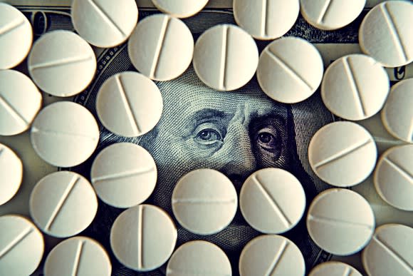 Prescription tablets covering up a hundred dollar bill, save for Ben Franklin's eyes.