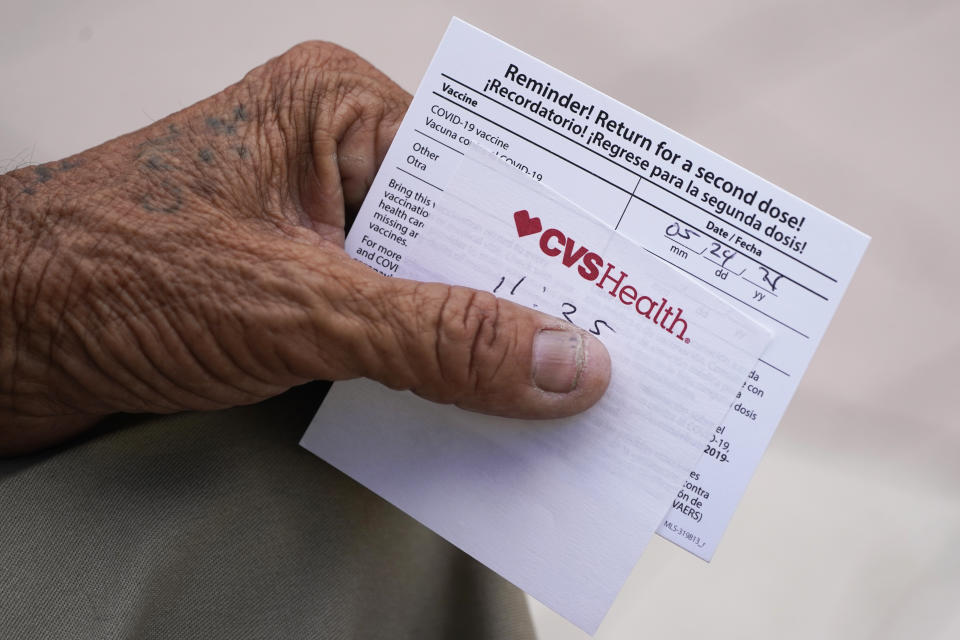 FILE - In this May 3, 2021 file photo, a man holds his vaccination reminder card after having received his first shot at a pop-up vaccination site in the Little Havana neighborhood of Miami. Billions more in profits are at stake for some vaccine makers as the U.S. moves toward dispensing COVID-19 booster shots to shore up Americans' protection against the virus. Drugstore chains CVS Health and Walgreens could bring in more than $800 million each in revenue, according to Jeff Jonas, a portfolio manager with Gabelli Funds. (AP Photo/Wilfredo Lee)