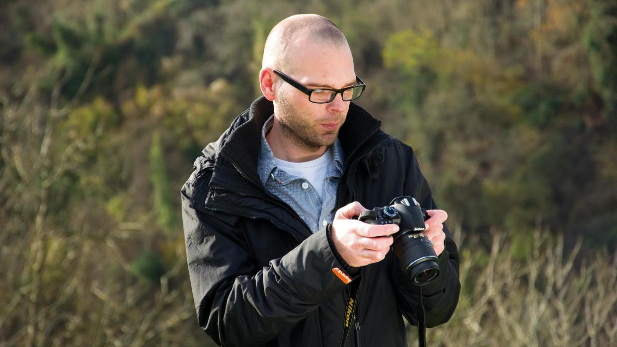  Man holding an entry-level Nikon DSLR camera 