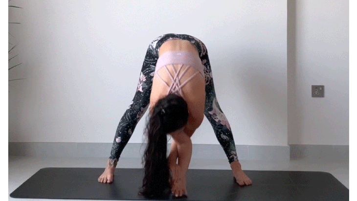 Woman standing on a yoga mat practicing a forward bend