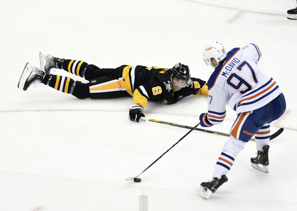 Edmonton Oilers center Connor McDavid (97) maneuvers the puck around Pittsburgh Penguins defenseman Brian Dumoulin (8) during the third period of an NHL hockey game, Thursday, Feb. 23, 2023, in Pittsburgh. The Oilers won 7-2. (AP Photo/Philip G. Pavely)