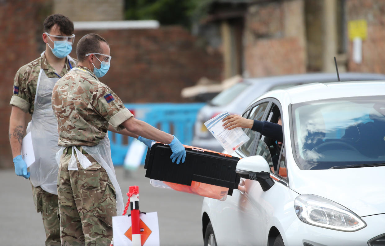 A driver wearing PPE hands a swab test to soldiers helping at a pop-up covid19 drive-through testing centre in Dalston, Hackney, east London, as the UK continues in lockdown to help curb the spread of the coronavirus. Picture date: Saturday May 2, 2020. 