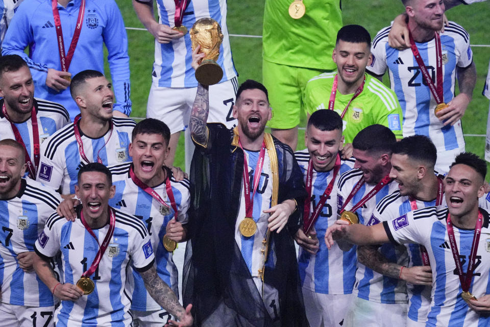 Argentina's Lionel Messi holds the trophy aloft as he celebrates with his team at the end of the World Cup final soccer match between Argentina and France at the Lusail Stadium in Lusail, Qatar, Sunday, Dec. 18, 2022. Argentina won 4-2 in a penalty shootout after the match ended tied 3-3. (AP Photo/Hassan Ammar)