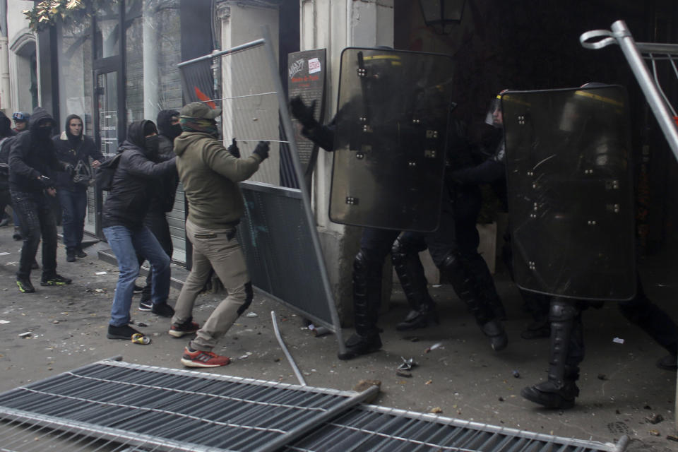 Youth clash with riot police officers during a demonstration in Paris, Thursday, Dec. 5, 2019. Small groups of protesters are smashing store windows, setting fires and hurling flares in eastern Paris amid mass strikes over the government's retirement reform. (AP Photo/Rafael Yaghobzadeh)