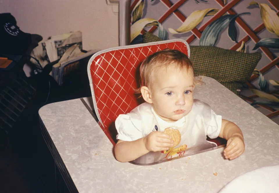 baby sitting in a highchair eating a cookie