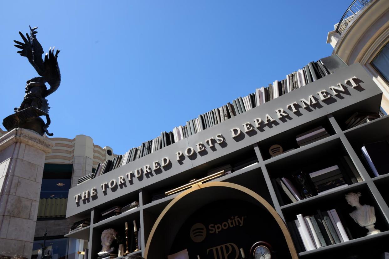 A gray and brown outdoor structure resembling a bookcase with the words "The Tortured Poets Department" near the top