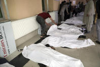 Afghan men try to identify the dead bodies at a hospital after a bomb explosion near a school west of Kabul, Afghanistan, Saturday, May 8, 2021. A bomb exploded near a school in west Kabul on Saturday, killing several people, many them young students, an Afghan government spokesmen said. (AP Photo/Rahmat Gul)