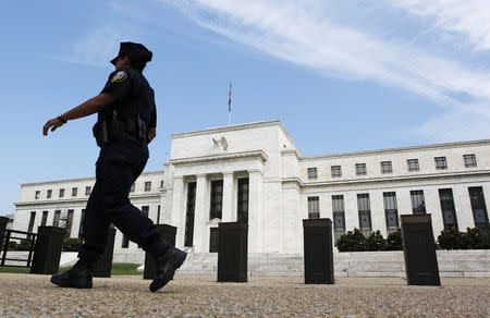 A police officer walks in front of the Federal Reserve in Washington August 22, 2012. REUTERS/Larry Downing/File Photo