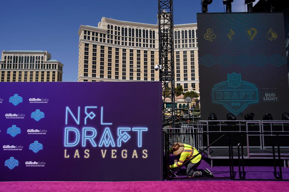 A worker on Tuesday helps erect a red carpet and stage in front of the Bellagio hotel-casino during setup for the NFL football draft in Las Vegas.