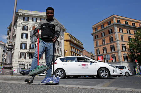 Christian Okoro of Nigeria sweeps a street in downtown Rome, Italy, May 18, 2017. Picture taken May 18, 2017. REUTERS/Max Rossi