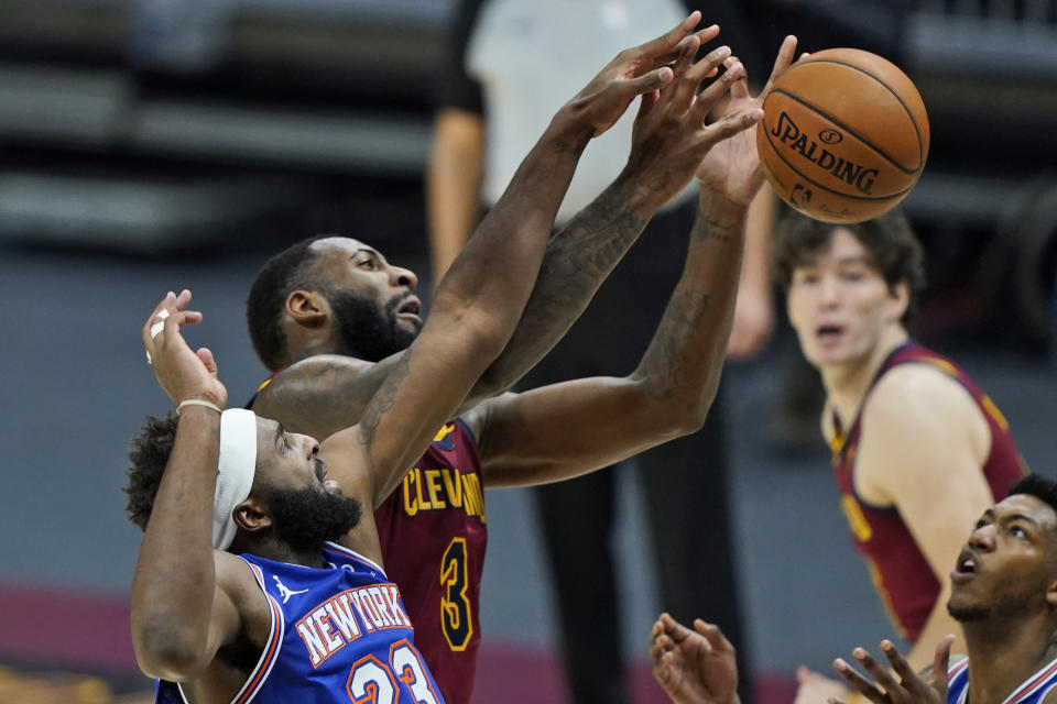 New York Knicks' Mitchell Robinson, left, and Cleveland Cavaliers' Andre Drummond reach for the ball during the second half of an NBA basketball game Friday, Jan. 15, 2021, in Cleveland. (AP Photo/Tony Dejak)