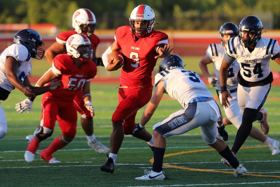 Monroe's Teegan Simmons fends off an Ann Arbor Skyline defender during a 58-0 Trojan win Thursday night.