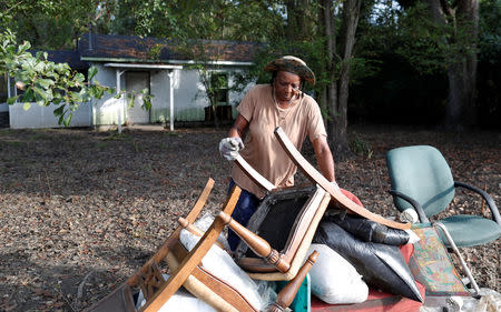 Katrina Bullock, who is still in the process of rebuilding after floods from Hurricane Matthew in 2016, stacks debris in front of her home after flooding due to Hurricane Florence receded in Fair Bluff, North Carolina, U.S. September 29, 2018. REUTERS/Randall Hill