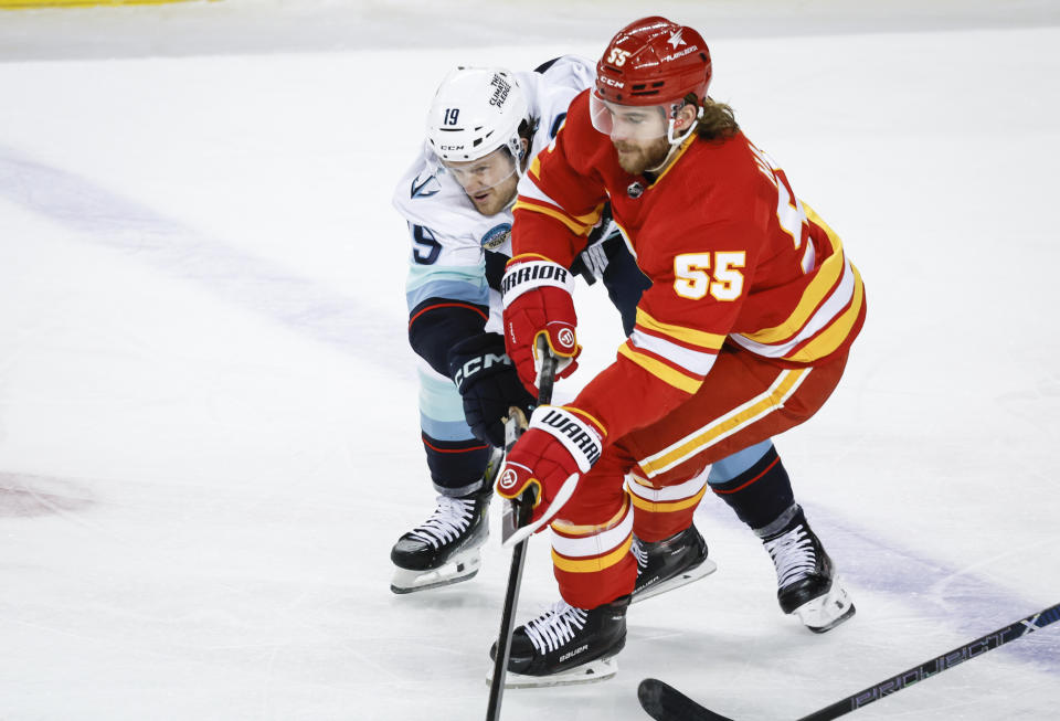 Seattle Kraken forward Jared McCann (19) checks Calgary Flames defenseman Noah Hanifin (55) during first-period NHL hockey game action in Calgary, Alberta, Monday, March 4, 2024. (Jeff McIntosh/The Canadian Press via AP)