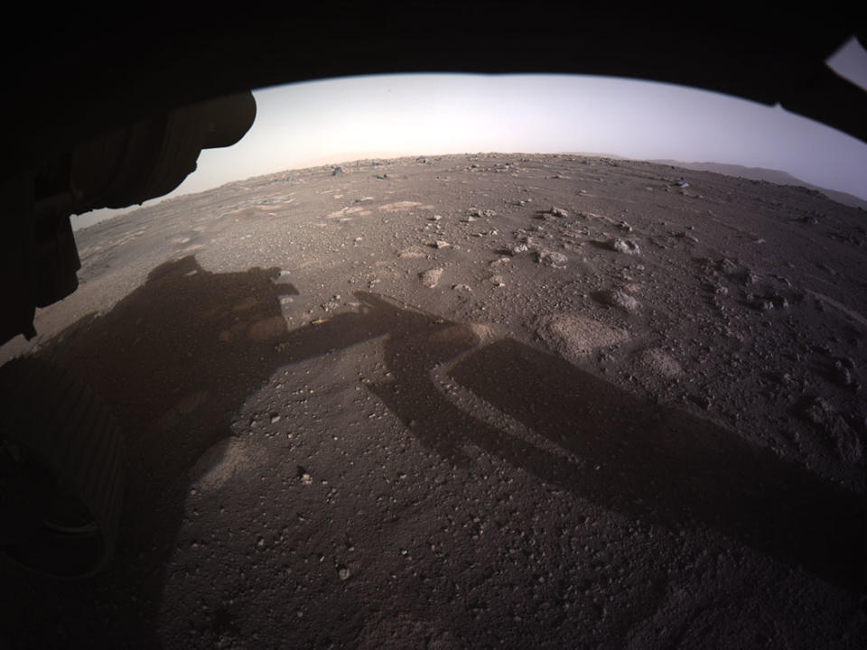 JEZERO CRATER, MARS - FEBRUARY 18:  In this handout image provided by NASA, the first high-resolution, color image to be sent back by the Hazard Cameras (Hazcams) on the underside of NASA’s Perseverance Mars rover after its landing in the area known as Jezero crater on February 18, 2021 on the planet Mars. A key objective for Perseverance's mission on Mars is astrobiology, including the search for signs of ancient microbial life. The rover will characterize the planet's geology and past climate, paving the way for human exploration of the Red Planet, and be the first mission to collect and cache Martian rock and regolith.  (Photo by NASA via Getty Images)