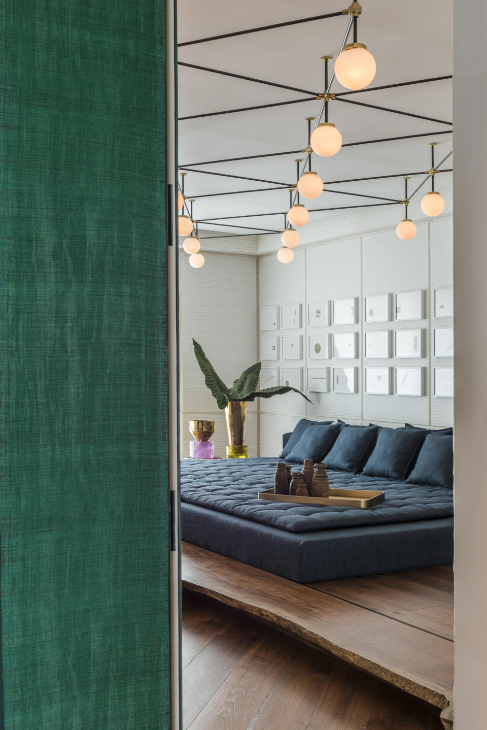 A bedroom with a cluster of lights above the bed