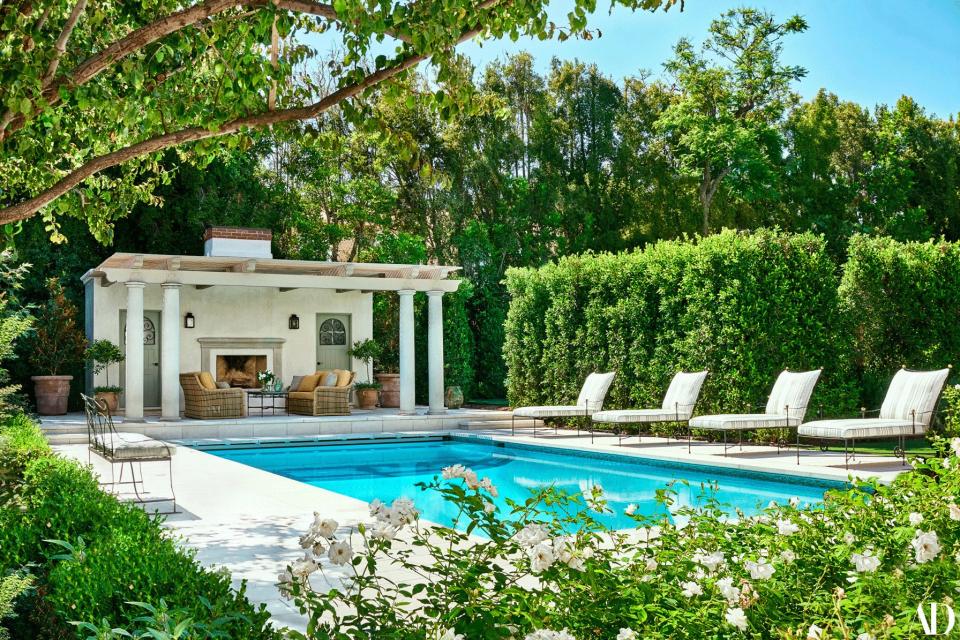 The pool deck features chaise longues by Janus et Cie. In front of the poolhouse, rattan sofas by Lane Venture in a Perennials acrylic.