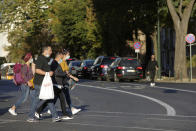 People wearing face masks cross a street in Lisbon, Friday, Oct. 16, 2020. Portugal has seen a steady increase in cases of COVID-19 in the past weeks. (AP Photo/Armando Franca)