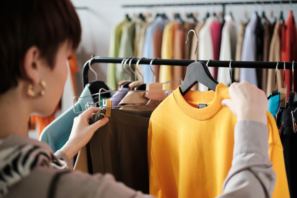 Rear view of young woman looking at clothes on rack in her hands