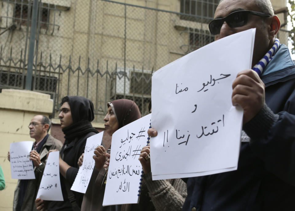 FILE - In this Feb. 6, 2016 file photo, mourners hold slogans at a vigil for slain Italian graduate student Giulio Regeni in front of the Italian embassy in Cairo, Egypt, Italian prosecutors on Thursday, Dec. 10, 2020 formally put three high-ranking members of Egypt’s national security force and one police officer under investigation in the 2016 kidnapping, torture and killing of an Italian youth doing doctoral research in Cairo. Arabic writing on posters reads, "Giulio is one of us and was killed like us" and "Giulio and El Gendi the same pain the same date." (AP Photo/Amr Nabil, file)