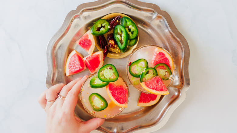 Hand holding one of two margarita glasses on a tray