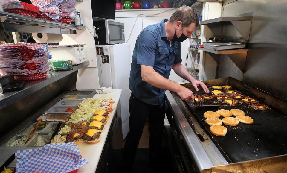 Casey Carson cooks up a grill full of Fat Smitty burgers for volunteers from Naval Base Kitsap-Bangor on Wednesday.