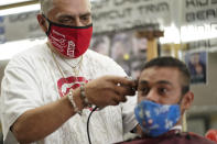 Edgar Gomez, right, has his hair cut by George Garcia, owner of George's Barber Shop, Tuesday, July 14, 2020, in San Pedro, Calif. Gov. Gavin Newsom ordered that indoor businesses like salons, barber shops, restaurants, movie theaters, museums and others close due to the spread of COVID-19. (AP Photo/Ashley Landis)