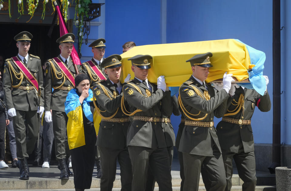 Soldiers carry a coffin with the remains of volunteer soldier Oleksandr Makhov, a well-known Ukrainian journalist, killed by Russian troops, at St Michael cathedral in Kyiv, Ukraine, Monday, May 9, 2022. The coffin is followed by Makhov's widow. (AP Photo/Efrem Lukatsky)