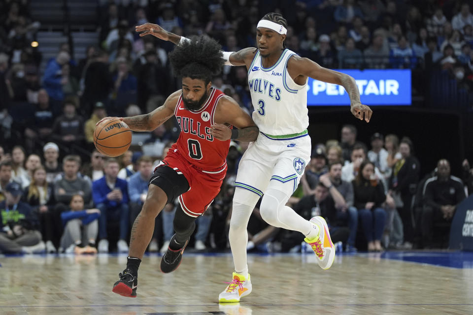 Chicago Bulls guard Coby White (0) works toward the basket as Minnesota Timberwolves forward Jaden McDaniels (3) defends during the first half of an NBA basketball game, Sunday, March 31, 2024, in Minneapolis. (AP Photo/Abbie Parr)