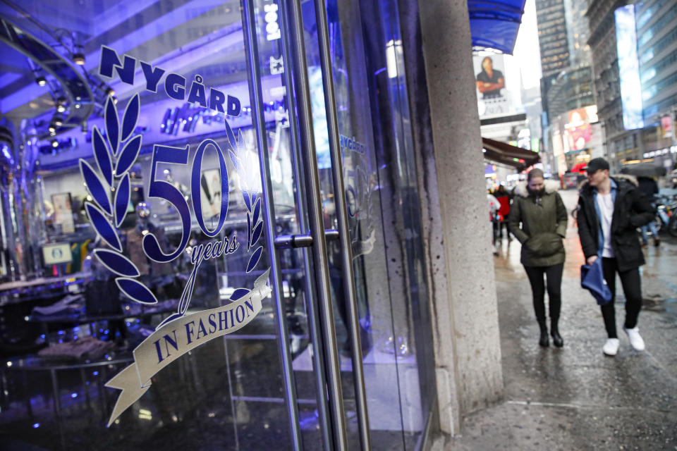 Pedestrians pass the storefront of Peter Nygard's Times Square headquarters, Tuesday, Feb. 25, 2020, in New York. Federal authorities on Tuesday, Feb. 25, 2020, raided the Manhattan headquarters of the Canadian fashion mogul Peter Nygard amid claims that he sexually assaulted and trafficked dozens of teenage girls and young women. (AP Photo/John Minchillo)