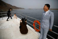 A couple gets ready for their wedding photo session on a boat that takes tourists from Chinese side of the Yalu River for sightseeing close to the shores of North Korea, near Dandong, China's Liaoning province, March 30, 2017. REUTERS/Damir Sagolj