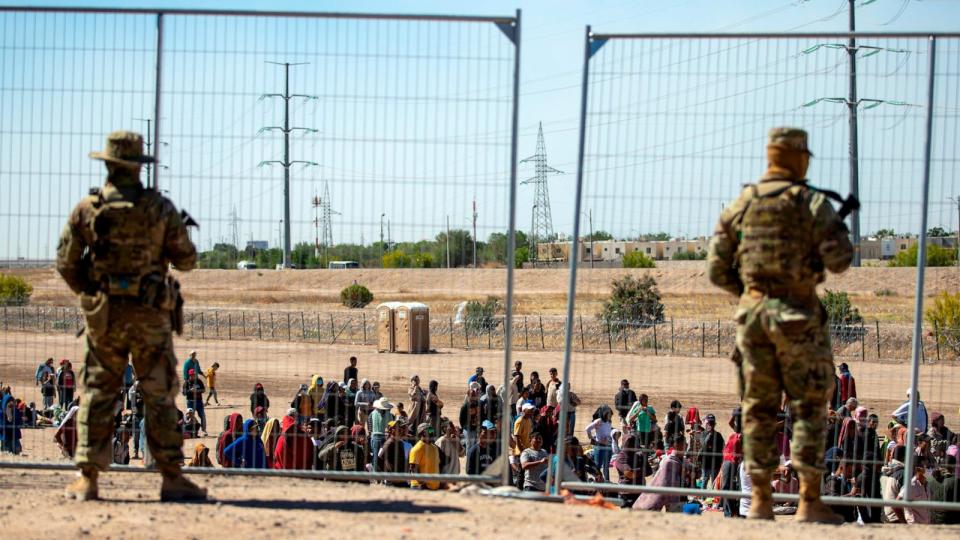 PHOTO: Migrants wait in line adjacent to the border fence under the watch of the Texas National Guard to enter into El Paso, Texas, May 10, 2023.  (Andres Leighton/AP, FILE)