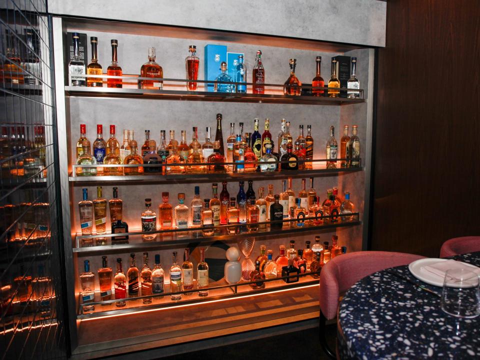 a wall of hard liquor by a dining table