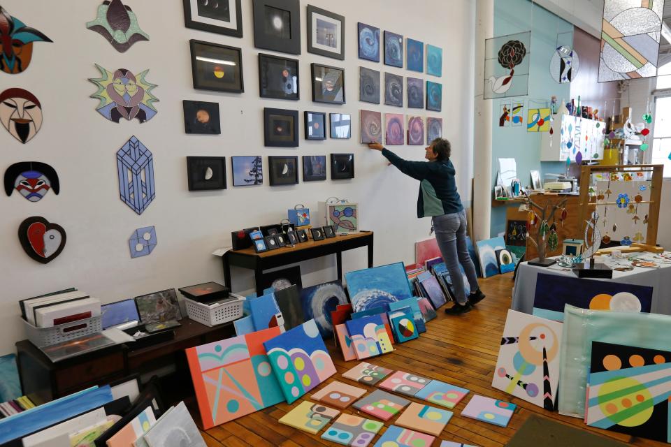 Michelle Lapointe hangs some of her paintings in her studio at Hatch Street Studios in New Bedford.