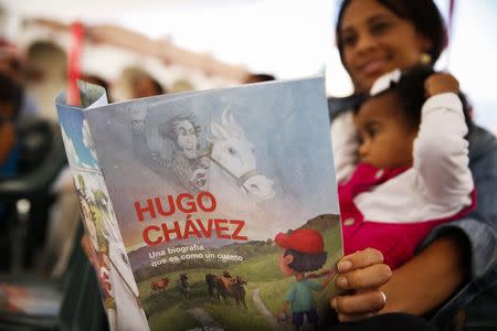 A woman holds a story book about the late Venezuelan President Hugo Chavez during a writing workshop at the 4F military fort in Caracas December 14, 2014. REUTERS/Carlos Garcia Rawlins