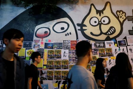 People walk past a Lennon Wall placed by anti-government protesters to commemorate the fifth anniversary of the Umbrella Movement, in Hong Kong