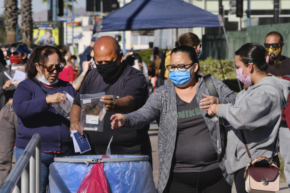 People drop their COVID-19 test kits into an intake receptacle after being tested at a site in the North Hollywood section of Los Angeles on Saturday, Dec. 5, 2020. With coronavirus cases surging at a record pace, California Gov. Gavin Newsom announced a new stay-at-home order and said if people don't comply the state's hospitals will be overwhelmed with infected patients.(AP Photo/Richard Vogel)